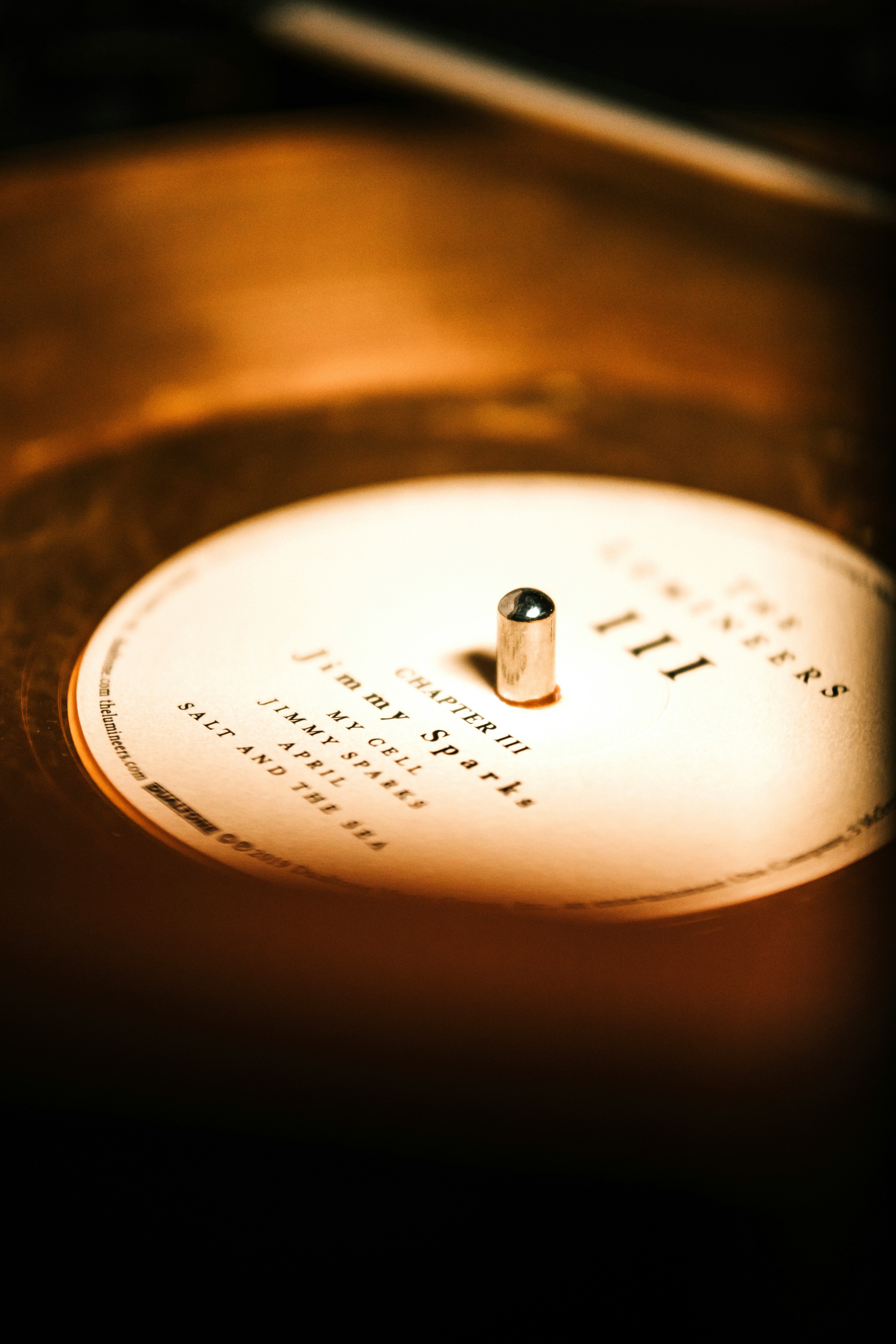 Étiquette d'un vinyle en gros plan sur une platine, lumière chaude et ambiance feutrée.