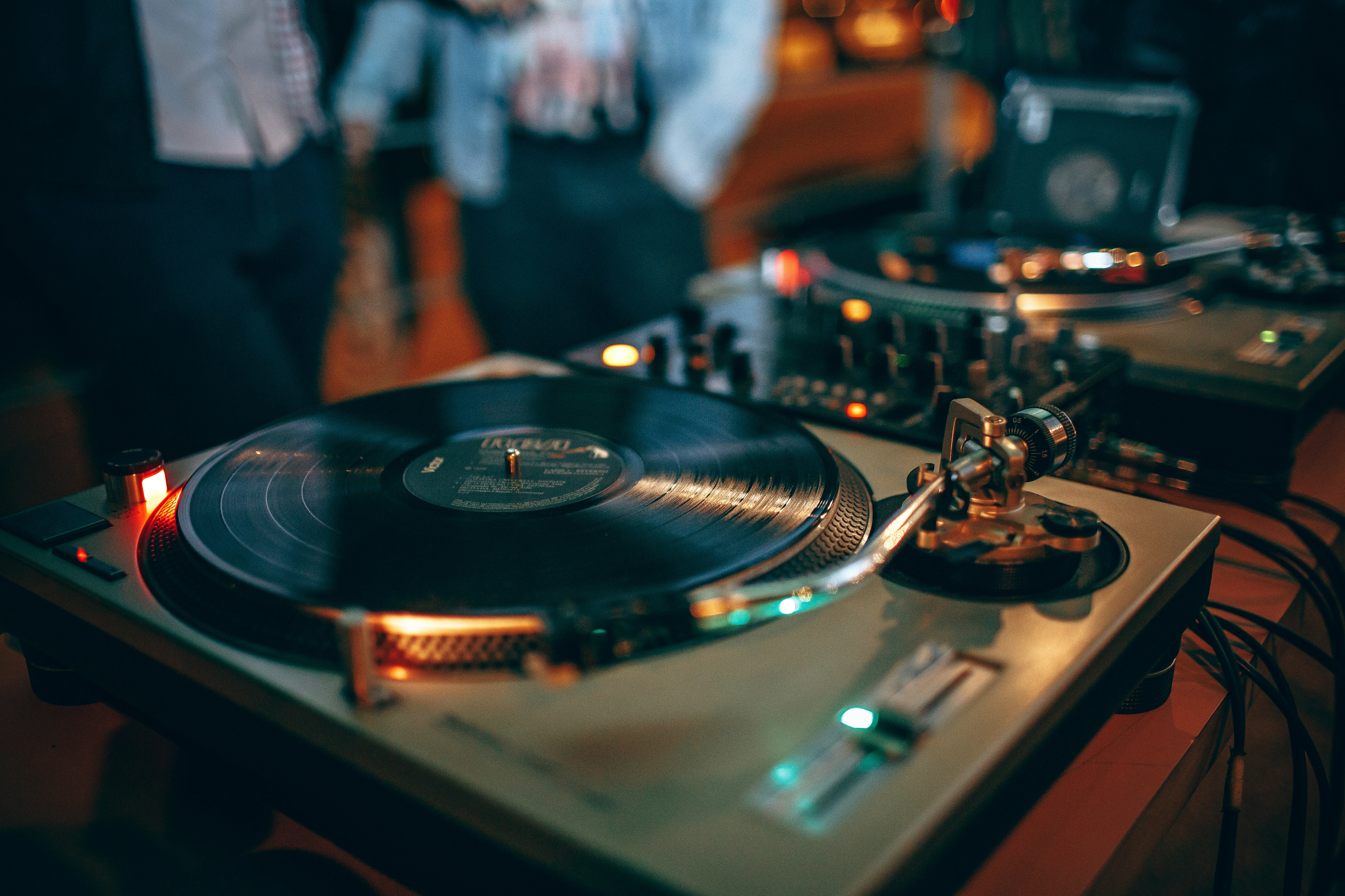 Platines vinyles en gros plan lors d'une soirée, disque en rotation et cellule de lecture.