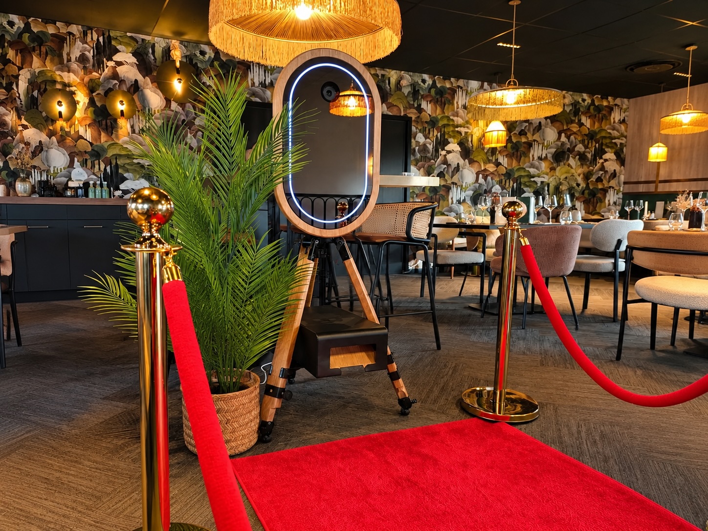 Photobooth miroir MODJA installé sur tapis rouge, entre deux poteaux de cordon VIP, dans un lieu de réception élégant.
