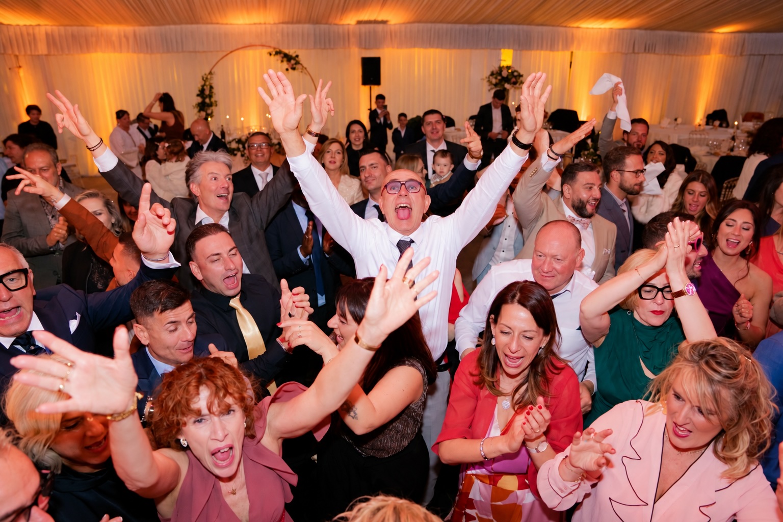 Invités en pleine effervescence sur la piste de danse, bras levés