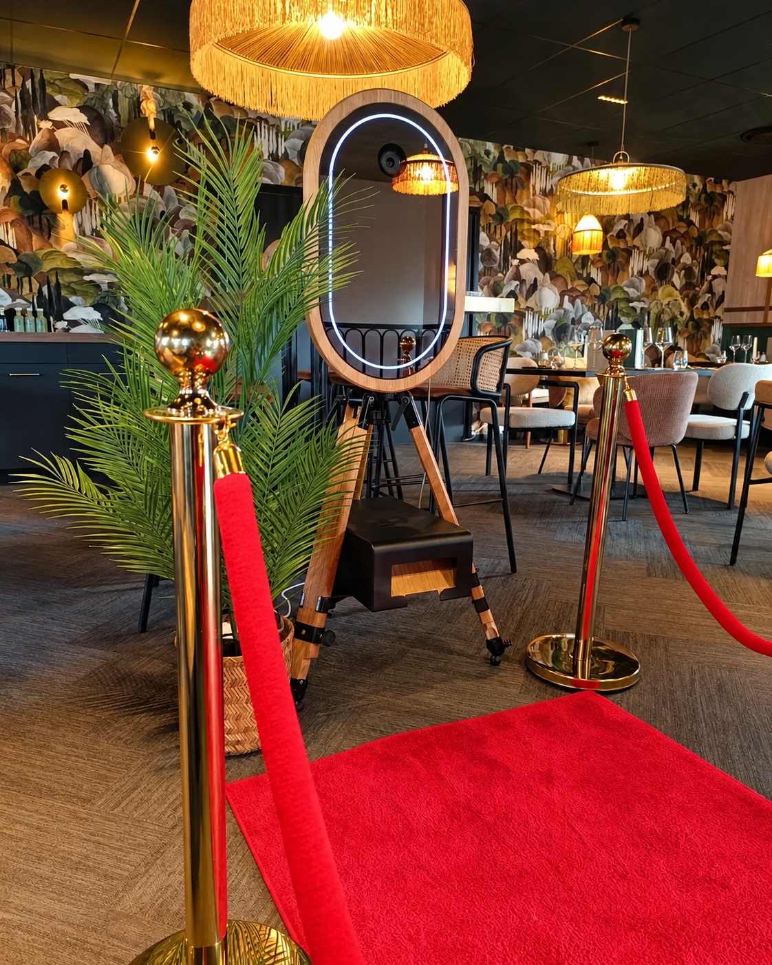 Photobooth miroir MODJA installé sur tapis rouge, entre deux poteaux de cordon VIP, dans un lieu de réception élégant.