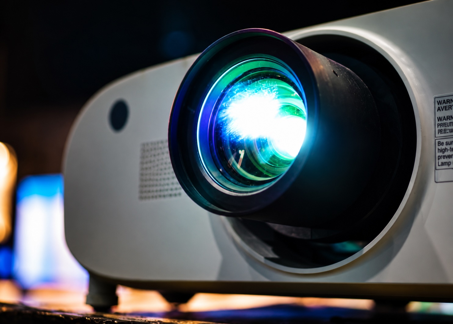 Gros plan sur l'objectif d'un vidéoprojecteur professionnel, faisceau lumineux allumé.
