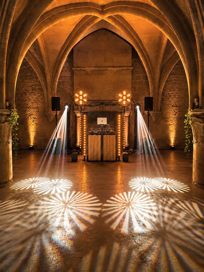 Installation Vintage Signature sous les voûtes en pierre, mise en lumière chaude, meuble DJ en bois.