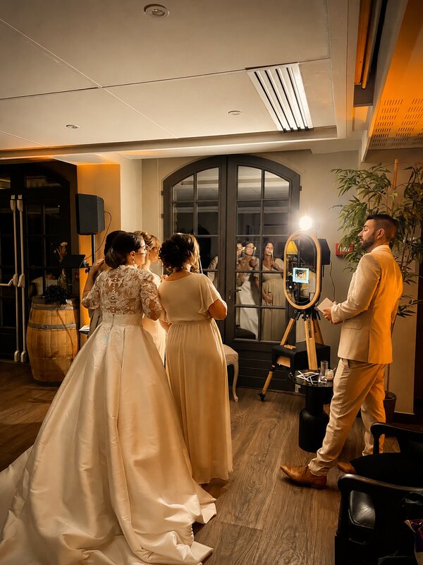 MODJA, le photobooth miroir en bois, entouré des mariés et invités lors d'une réception.